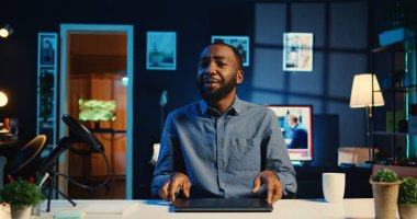 Afro-amerikan içerik yaratıcısı yeni çıkan dizüstü bilgisayarın görüntülerini kaydediyor, paketini açıyor ve izleyicilere sunuyor. İzleyicilere çok ince bir not defteri gösteren bir etken