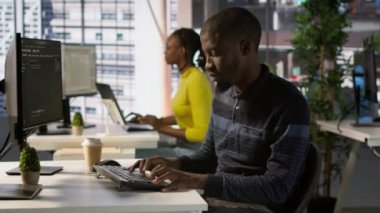 Programcı yazılım hata ayıklama yapıyor, tekerlekli sandalyedeki gülümseyen takım liderinden yardım istiyor. Çalışan kodlama hatalarını düzeltir, engelli neşeli yönetici tarafından yardımcı olunur, kamera A