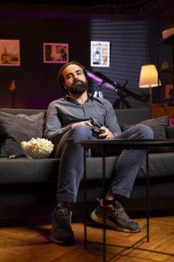 Oyuncu gecenin geç saatlerinde neon ışıklı odada konsolda video oyunları oynuyor, uyanık kalmak için çabalıyor. Uyumadan önce oyun görevini tamamlamak için joystick kumandası kullanan bir adam