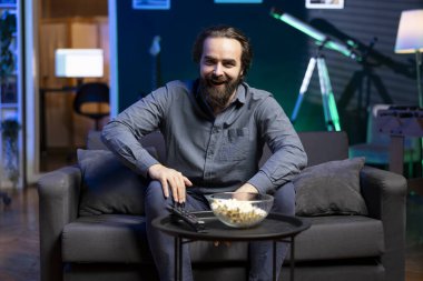 Kablo kesicinin TV 'nin önünde patlamış mısır yiyip film izleyip güldüğü portre. Evde oturup televizyon ekranındaki talep üzerine komedi şovları izleyen eğlenceli bir insan.