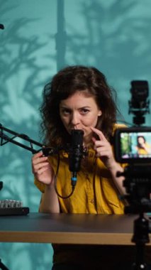 Dikey video İçerik oluşturucu hayranlar için ASMR tipi bir video hazırlıyor, profesyonel kamerayla kaydediliyor. Rahatlatıcı video oluşturmak için gelişmiş mikrofon ve çekim teçhizatı kullanan çevrimiçi şov sunucusu