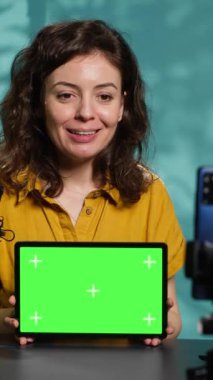Dikey video iyimser teknoloji uzmanı yeni fırlatılan yeşil ekran tableti elinde tutuyor. Neşeli internet yıldızı, izleyiciler için taşınabilir dijital aygıt incelemesi yapıyor