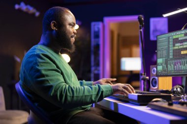 Sound engineer pressing keys of electronic synthesizer and composing new song, adjusting volume levels on pre amp knobs. Composer producing music on piano midi controller, mixing tunes. clipart