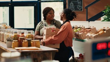 Employee receiving products from farmers daughter, dealing with supplying the local grocery store with freshly harvested produce. African american vendor acquiring more eco friendly merchandise.