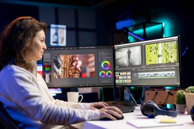 Gülümseyen video editörü, çekim görüntülerini güncellemek için kurgu yazılımı kullanıyor, yapım ekipleri tarafından dış kaynak görevleri için yaptırılıyor. Daire stüdyosundaki mutlu videocu projesini bitiriyor.