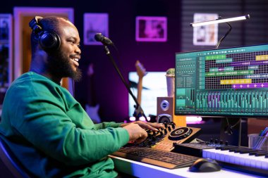 Ev stüdyosunda karıştırma konsolu ile çalışan yetenekli ses mühendisi, bir melodi için yeni soundtrack 'ler üretiyor ve ses tasarımcısı seviyelerini ayarlıyor ses tasarımcısı dosyaları, sinyal işleme.