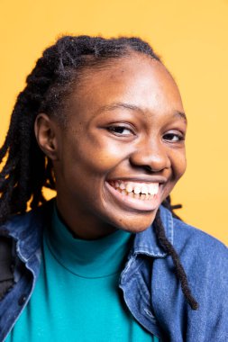 Neşeli Afro-Amerikan kadın portresi gülümseyen, minnettar hisseden, stüdyo arka planında soyutlanmış. Canlı ışık saçan BIPOC genci sırıtıyor, iyi haberlerin tadını çıkarıyor, yakın çekim