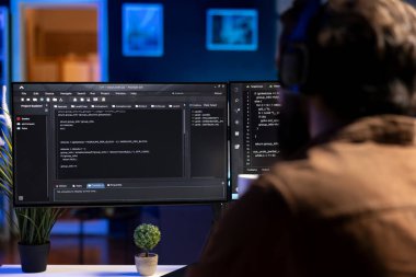 Yazılım kalitesi güvencesi veren adam uygulamadan önce bilgisayar ekranında kaynak kodunu okuyor. Masaüstü bilgisayarında kodlamayı denetleyen geliştirici, potansiyel sorunları düzeltmeye çalışıyor