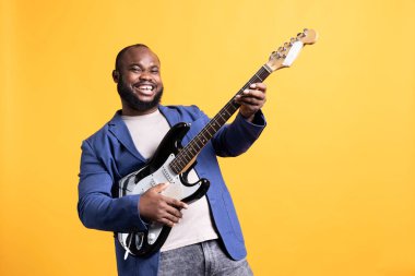 Neşeli adam elektro gitarda sallanıyor, konser veriyor, stüdyo arka planında izole halde. Neşeli müzisyen müzik enstrümanında rock müzik yapıyor, performanstan memnun.
