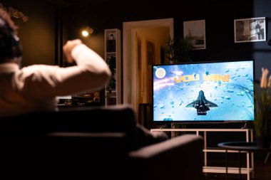 Oyuncu, oyun konsolu kazandıktan sonra ultra akıllı TV 'de gösterilen oyunu kutluyor. Apartmandaki adam video oyununda kazandıktan sonra övünüyor, oyun sahasını kullanarak seviyeyi tamamlıyor
