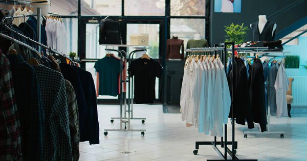 Shopping mall prepared with stock of new fashion collection line, multiple racks with fashionable wear and modern accessories. Empty clothes showroom with trendy items, small business. Camera B.