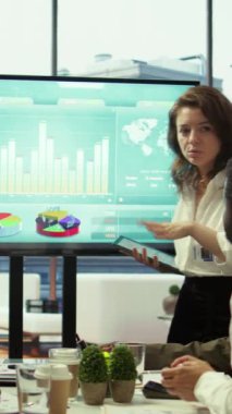 En son bütçe raporları ve veri görselleştirme araçları kullanılarak proje amaçlarına ulaşmak için, işbirlikçi toplantı sırasında bir tablette bilgi grafikleri üzerinde çalışan Dikey Video Örgütsel personel. Kamera B.