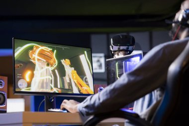 PC monitöründe FPS siber uzay video oyunları oynayan Afrikalı bir Amerikalı. Klavye ve fare reklamı kullanan, masadaki bilgisayarda oyun oynayan, eğlenen bir adam.