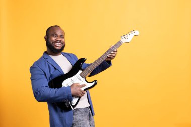 Gitar tutan mest olmuş bir adamın portresi, konser sırasında rock şarkıları söylemek için heyecanlı, stüdyo arka planında izole edilmiş. Neşeli sanatçı, elektro müzik enstrümanında metal şarkılar söylemekten zevk alır.
