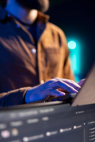 Teleworking programmer doing software debugging using laptop, checking flaws in lines of code displayed on PC monitors. IT admin in apartment fixing coding issues using notebook, close up