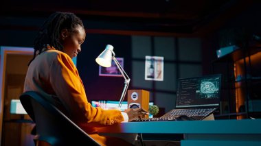 Afro-Amerikan sistem mühendisi bilgisayar programı kodu yazmak için yapay zeka sistemini kullanıyor, html terminal penceresi. Kadın derin öğrenme algoritmalarıyla, yapay zeka sinir ağlarıyla çalışıyor. Kamera B.