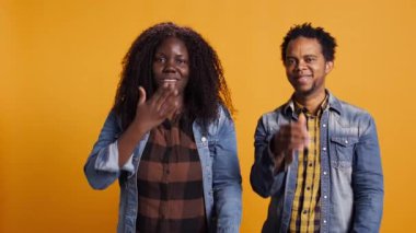 Şirin evli çift hava öpücüğü yolluyor ve birlikte poz veriyorlar, gülümsüyorlar ve birbirlerine minnettarlar. Afrikalı Amerikalı erkek ve kadın stüdyoda flört ediyorlar. Kamera B.