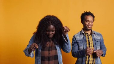 Güzel, neşeli karı koca stüdyoda dans ediyor ve birlikte eğleniyorlar. Sarı arka planda komik dans figürleriyle aptalca davranıyorlar. Acayip evli insanlar. Kamera B.