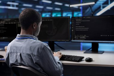 Yazılım programcısı veri merkezi donanımında olası bir arıza var mı diye kontrol ediyor. Bıçak sunucularının hasarını önlemek ve kritik sistemleri izlemek için bilgisayar masasında çalışan bilişim uzmanı