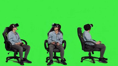 Kadın kumanda ve vr kulaklıkla konsolda video oyunları oynuyor, yeşil ekran arka planına karşı oturuyor. Oyuncu çevrimiçi turnuva, sanal gerçeklik etkileşimli siber uzay ile eğleniyor. Kamera A.