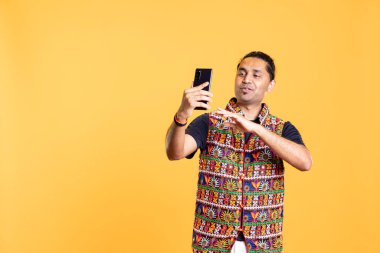 Gülümseyen Hintli adam akıllı telefondan en iyi arkadaşıyla konuşuyor. Telekonferansta arkadaşla konuşan neşeli kişi cep telefonuyla görüşüyor, stüdyo arka planında izole edilmiş.