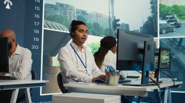 Hintli bir çalışan gözlem odasındaki uydu haritası yönlerini bildiriyor, CCTV güvenlik sisteminden şehrin etrafındaki trafiği izliyor. Genç adam video izleme verileriyle çalışıyor. Kamera B.