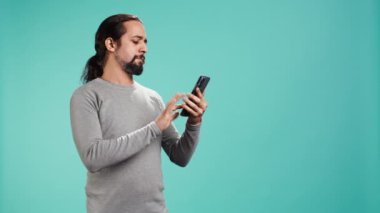 Arkadaşlarıyla telefon görüşmesinde konuşan gülümseyen bir adamın portresi. Akıllı telefon, stüdyo geçmişi. Neşeli insan telefon görüşmesi sırasında iyi haberler aldıktan sonra pozitif hissediyor, kamera B