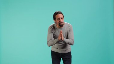 Adam özür dilemek için el ele tutuşup af diliyor. Özür dileyen kişi üzgün hareketler yapıyor, özür diliyor, stüdyo arka planında izole edilmiş, kamera A