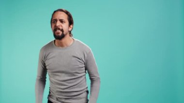 Öfkeli bir adamın portresi öfkeli, arkadaşına bağıran, bastırılmış duygularını açığa çıkaran, stüdyo arkaplanı. Öfke dolu öfkeli insan, mavi stüdyo arka planında izole edilmiş arkadaşına bağırıyor, kamera B