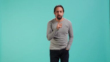Şşş yapan bir adamın portresi el hareketi yapıyor, sessizlik talep ediyor. Dudaklara parmak basan, sessiz işaret hareketi yapan, gizlilik isteyen, stüdyo arka planında izole edilmiş, kamera A
