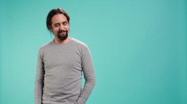 Neşeli, kendine güvenen bir adam kameraya göz kırpıyor, flört ediyor. Dudaklarını ısıran, aşk çocuğu gibi davranan, romantik jestler yapan, stüdyo arka planında izole edilmiş, kamera B