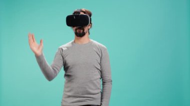 Teknoloji meraklısı sanal gerçeklik gözlüğü takıyor, jestler yapıyor. Arap adam ileri teknoloji modern VR gözlükleri kullanıyor, dokunaklı hareketler yapıyor, stüdyo arka planı, kamera B