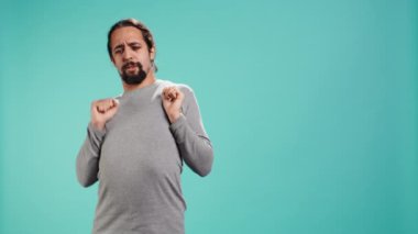 Vücudunu geren bir adamın portresi, kaslarda yorgunluk ve gerilim hisseder. Stres atmak için uzuvlarını esneten burkulmuş bağları olan yorgun insan, stüdyo arka planı, kamera B