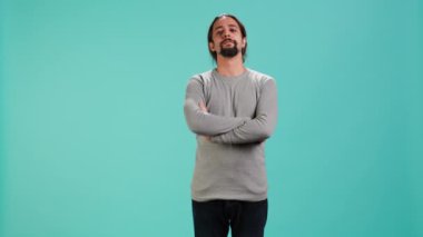 Suratında somurtkan bir ifade olan huysuz bir adam kollarını kavuşturuyor. Sinirli ve stüdyo arka planında soyutlanmış hissediyor. Sinirli bir insan portresi. Kötü bir ruh hali. Tartışma sonrası hayal kırıklığı.