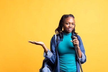 Motivasyon konuşmacısı portresi mikrofonla konuşuyor, dinleyicilere hitap ediyor, el kol hareketleri yapıyor, stüdyo geçmişi var. Kendine güveni olan BIPOC kadını mikrofon kullanıyor.