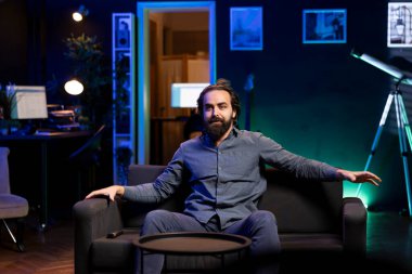 Televizyonda dizileri izleyen heyecanlı bir adam, çenesini düşüren bir olaya kapılmış, koltuğun kenarında oturuyor. Evdeki koltukta oturan neşeli adam, şok edici film senaryosundan şaşkına döndü.