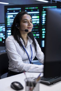 Neşeli veri merkezi operatörü. Mühendislik ekibini destekliyor. Ekip bakımını yapıyor, mikrofonla konuşuyor. Sunucu odasında gülümseyen kişi mikrofon kullanarak teknisyenleri koordine ediyor.