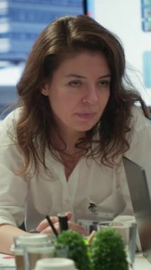 Dikey Video Finans uzmanı konferans odasındaki belgelerle ilgili istatistik verilerini gösteriyor, sunum için personelle brifing veriyor. Pazar ihtiyaçlarına uyum sağlamak için satış raporlarını inceleyen iş arkadaşları