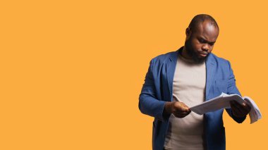 Adam mali denetim raporlarına göz atıyor, onları öfkeyle atıyor, çok çalıştığını hissediyor, stüdyo geçmişi var. Stresli işçi çok fazla evrak işlerinden rahatsız, çalışmayı reddediyor, kamera B