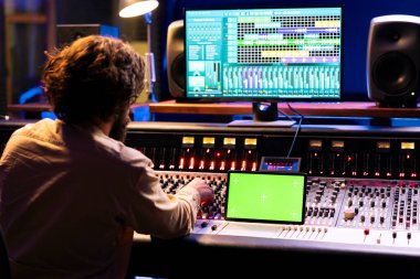 Kontrol odasında yeşil ekran, düzenleme ve işleme ile tabletin yanındaki yetenekli ses tasarımcısı kayıt melodileri. Müzik mühendisi, albüm hazırlamak için kaydırma ve düğme kullanıyor..