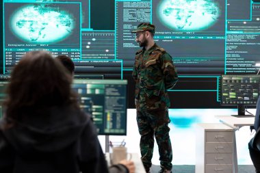Hükümet ordu hackerları teşkilat ofisinde melez savaş stratejileri uyguluyor. Bilgi toplamak, saldırıları önlemek ve askeri operasyonları korumak için yazılım ve teknoloji kullanan personel.