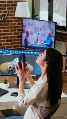 Dikey Video Asyalı profesyonel mühendis gelişmiş yazılım araçları kullanarak endüstriyel tasarımlar üzerinde çalışıyor. Oturma odasında çift monitörler ve yüksek verimlilik için teknik ekipmanlar bulunmaktadır.