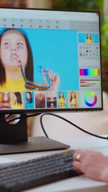Dikey Video Uzmanı kadın yaratıcı bir ofiste bilgisayarındaki dijital fotoğrafları düzenliyor. Düzenleme yazılımıyla donatılmış çalışma alanı, endüstrideki sanatsal çalışmaları geliştiriyor. Kamera B.