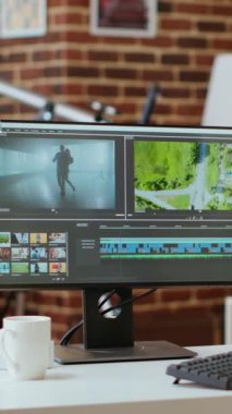 Dikey Videolu Asyalı film yapımcısı kadın kulaklık takıyor ve video yapımında çalışıyor, video klipleri karıştırıyor. Renk derecelendirmesi için mükemmel bir yazılıma sahip ofis kurulumu