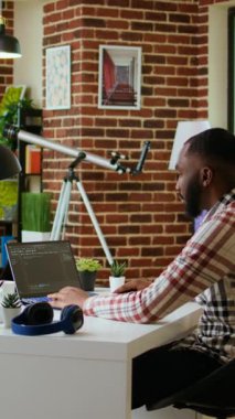 Dikey Video Afrikalı Amerikalı yazılım geliştiricisi uzak çalışma alanındaki bir dizüstü bilgisayarda programlama kodu üzerinde çalışıyor. Üretken bilişim mühendisi kodlama, yazılım tasarımı ve internet güvenliği yeniliği üzerinde çalışıyor