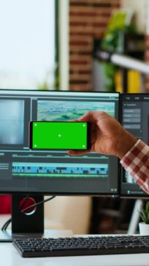 Dikey Video Erkek Film Yapımcısı, modern bir renk derecelendirme yazılımında bir video projesini fotokopi ekranı kullanarak düzenliyor. Genç adam video yapımının yaratıcı sürecinde çift monitörlerde çalışıyor.
