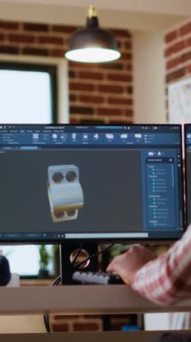 Dikey video Afrikalı Amerikalı endüstriyel tasarımcı yaratıcı bir stüdyoda prototipler üzerinde çalışıyor. 3D modelleme ve CAD yazılımı ile uzaktan kumandalı teknoloji kullanımı, teknik hassasiyet için endüstriyel araçlar