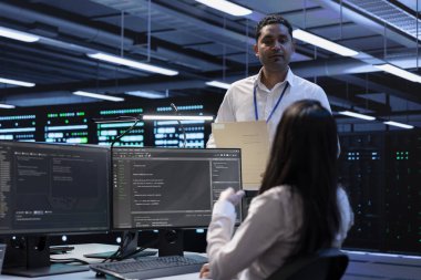 Veri merkezindeki mühendislerden oluşan bir ekip sunucuları etkileyen güvenlik duvarı yapılandırmalarını arıyor. Sunucu odasındaki çok ırklı işçiler sistem denetim sistemlerini kontrol ederken, veri aktarım hızları yavaşlıyor