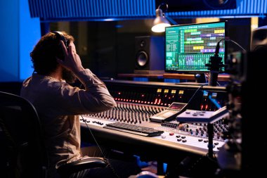 Sound engineer using headset to edit tracks on audio digital software, producer creates music and handling technical gear on control room dashboard. Technician does mix and master. clipart