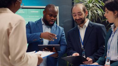 Denetmen ve çalışanlar, mevcut iş projesindeki ilerleme portföyleriyle birlikte statü güncelleme toplantısına katıldılar. Takım lideri pazarlama stratejilerini ve bütçe planlamasını gözden geçiriyor. Kamera A.